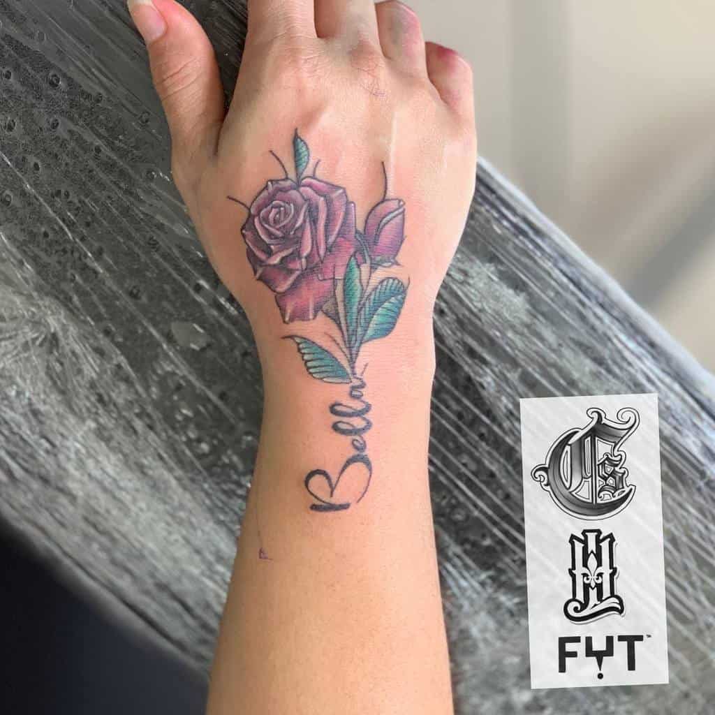 Hand tattoo featuring a detailed red rose with green leaves and the word "Bella" elegantly scripted along the stem
