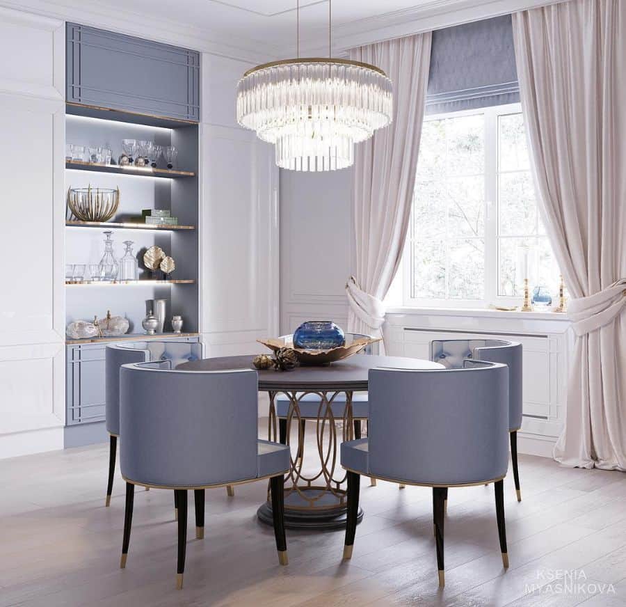 round dining room table blue chairs thick curtains recessed shelving large glass chandelier