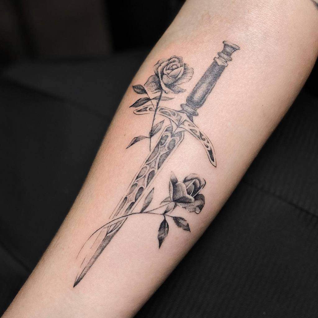 Tattoo of a sword entwined with roses on someone's forearm in detailed single needle style