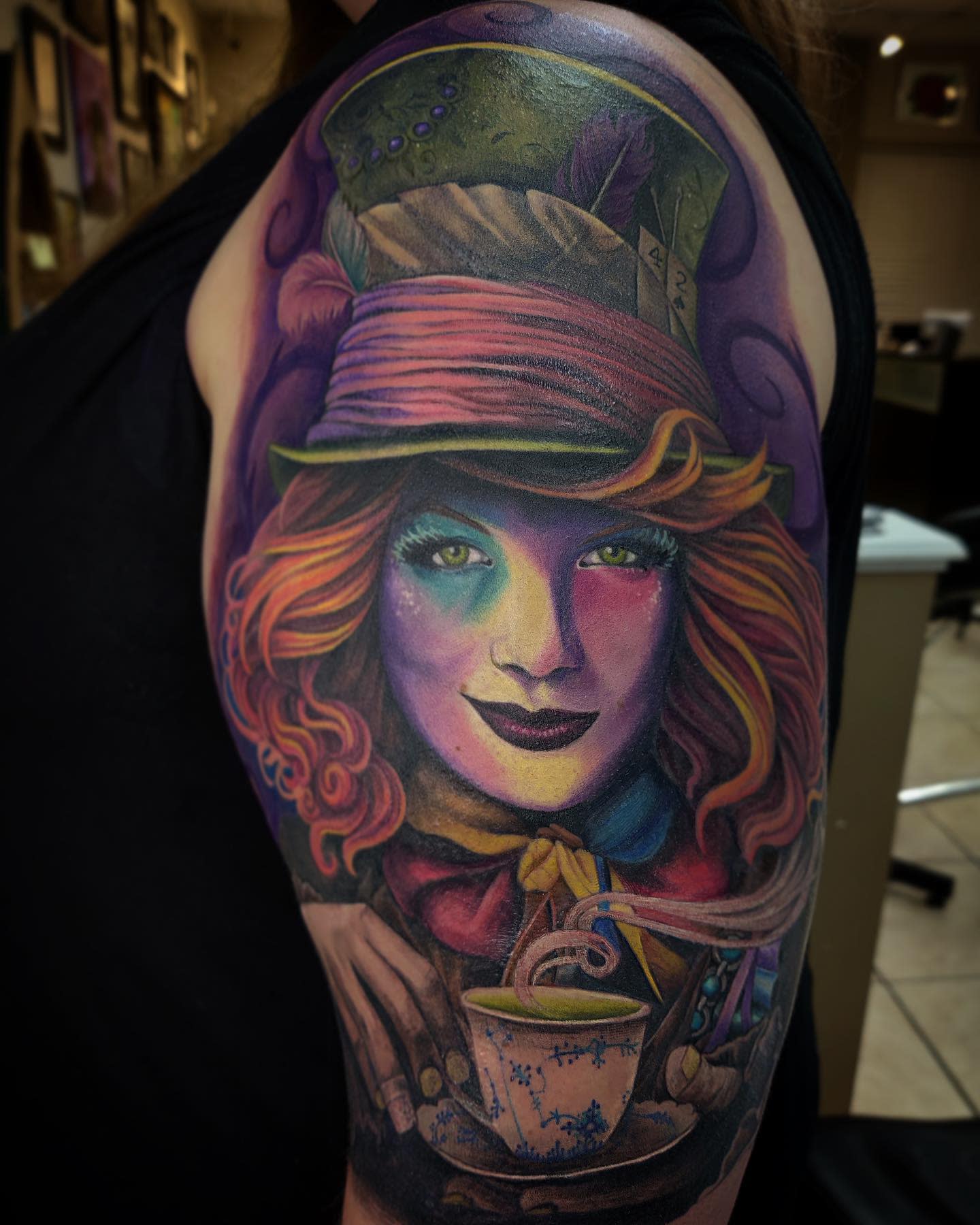Vibrant, colorful tattoo of the Mad Hatter holding a teacup, showcasing his whimsical and lively nature