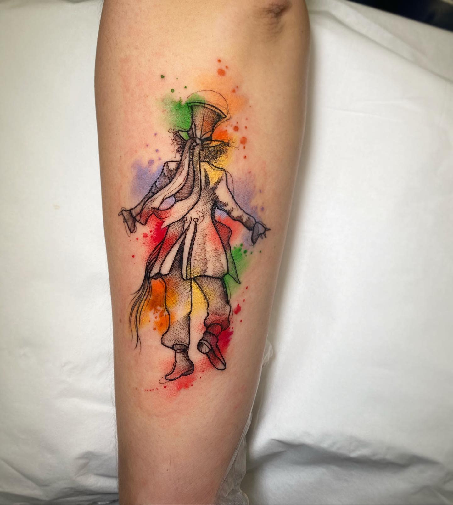 Watercolor tattoo of the Mad Hatter from behind, with splashes of vibrant colors highlighting his whimsical figure