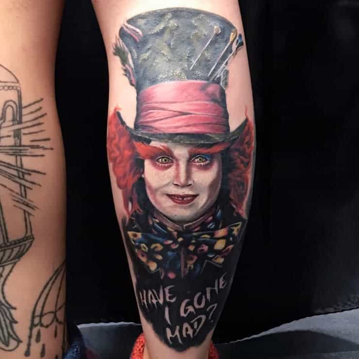 Realistic tattoo of the Mad Hatter from Alice in Wonderland, featuring Johnny Depp's likeness, and the quote 'Have I gone mad?' written below