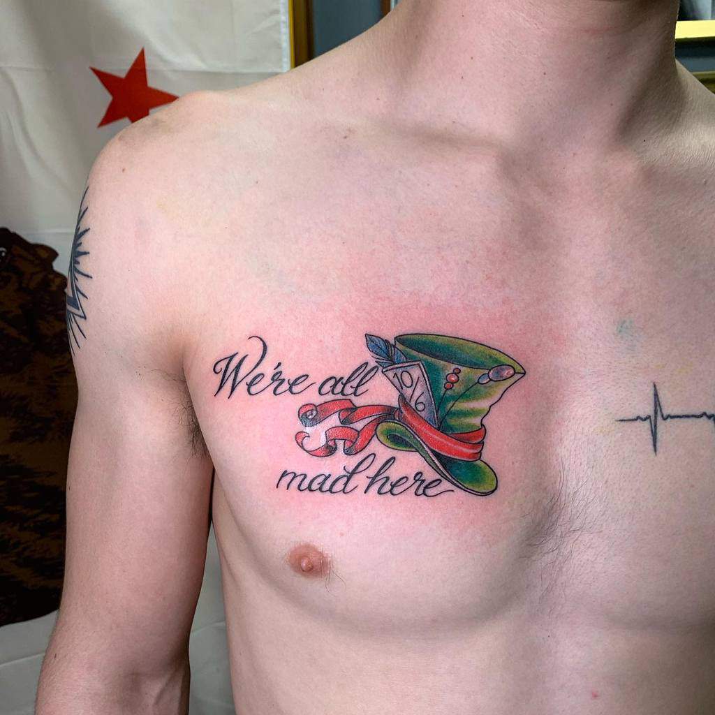 Colorful tattoo of the Mad Hatter’s hat from Alice in Wonderland, with the quote 'We're all mad here' and a ribbon wrapping around the hat, featuring the '10/6' price tag