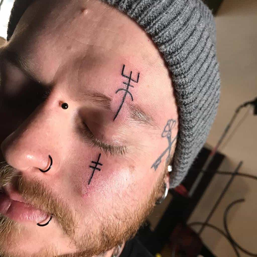 A man with tribal-inspired face tattoos, including minimalist line designs