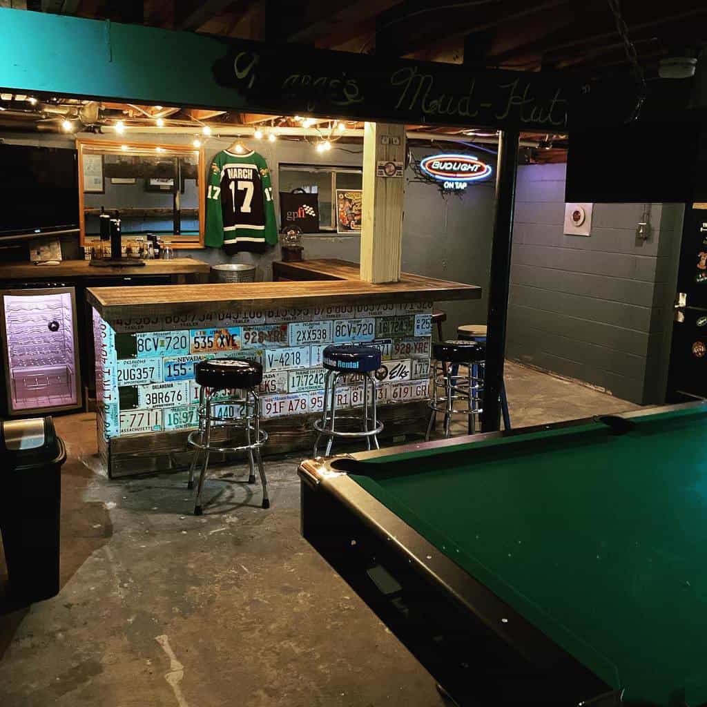 Man cave basement bar with license plate decor, pool table, and sports memorabilia on display.