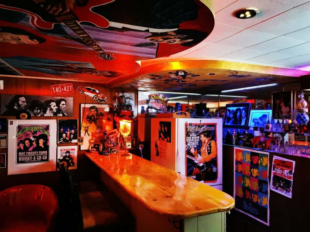 Music-themed man cave with posters, memorabilia, and a wooden bar surrounded by vibrant decor.