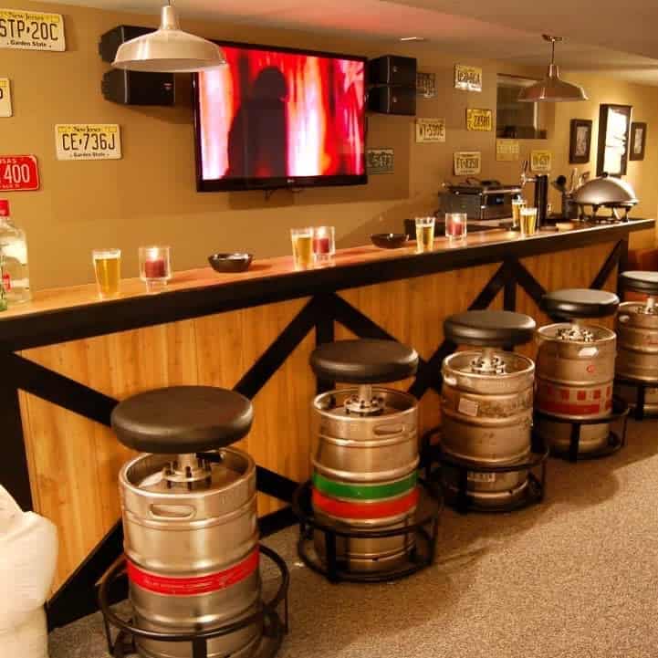 Basement bar with keg stools, wooden counter, and license plates decorating the walls.