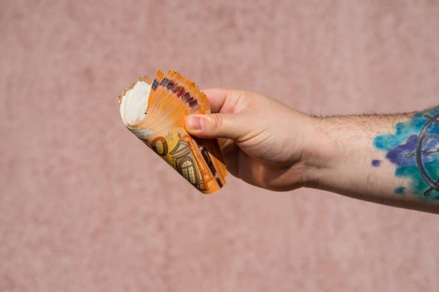 Man with tattoo heands over cash