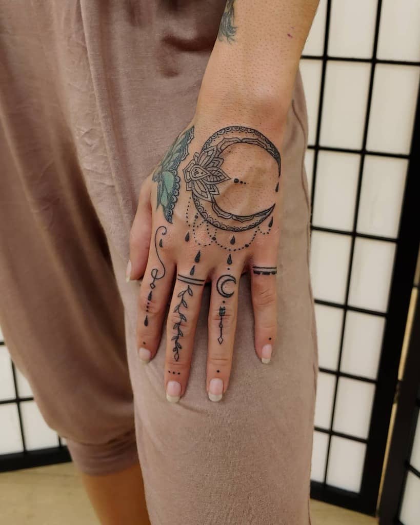 Crescent moon and geometric tattoos on a hand