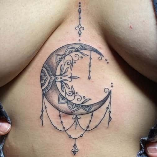 Detailed crescent moon tattoo with ornate designs and hanging jewels elegantly gracing a chest