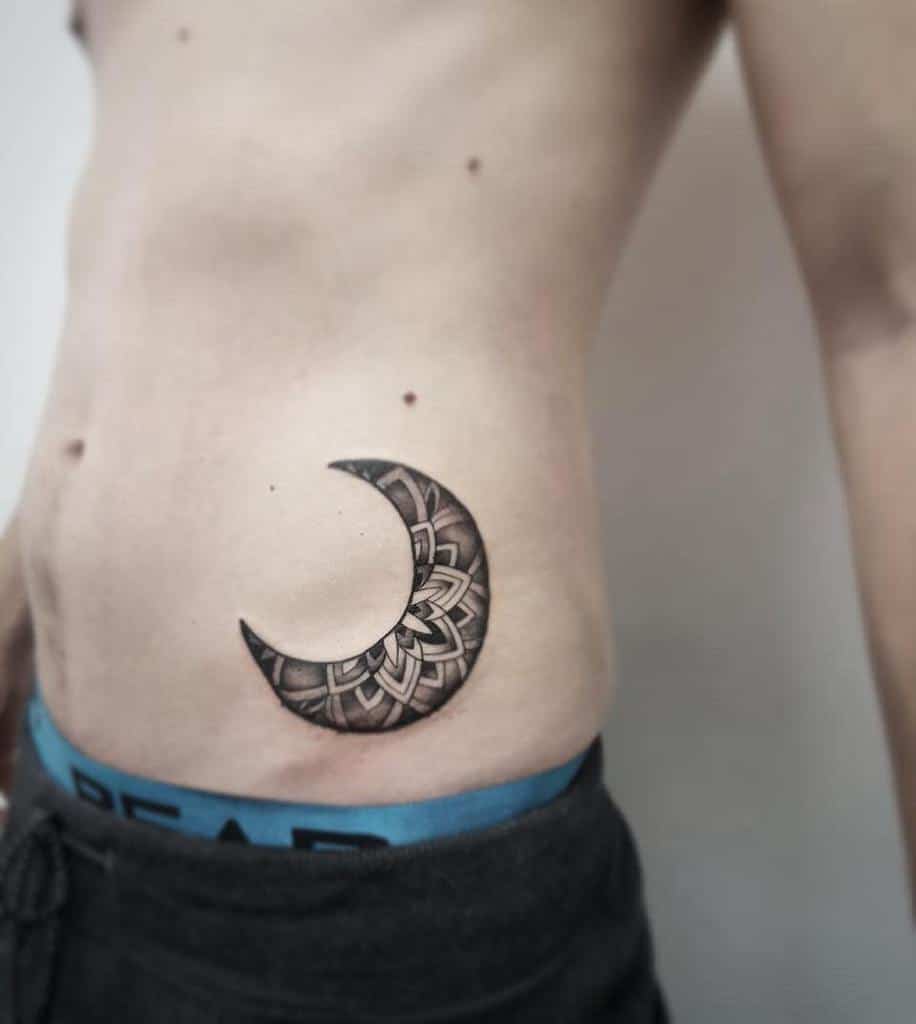 Intricately detailed crescent moon tattoo on left side midsection
