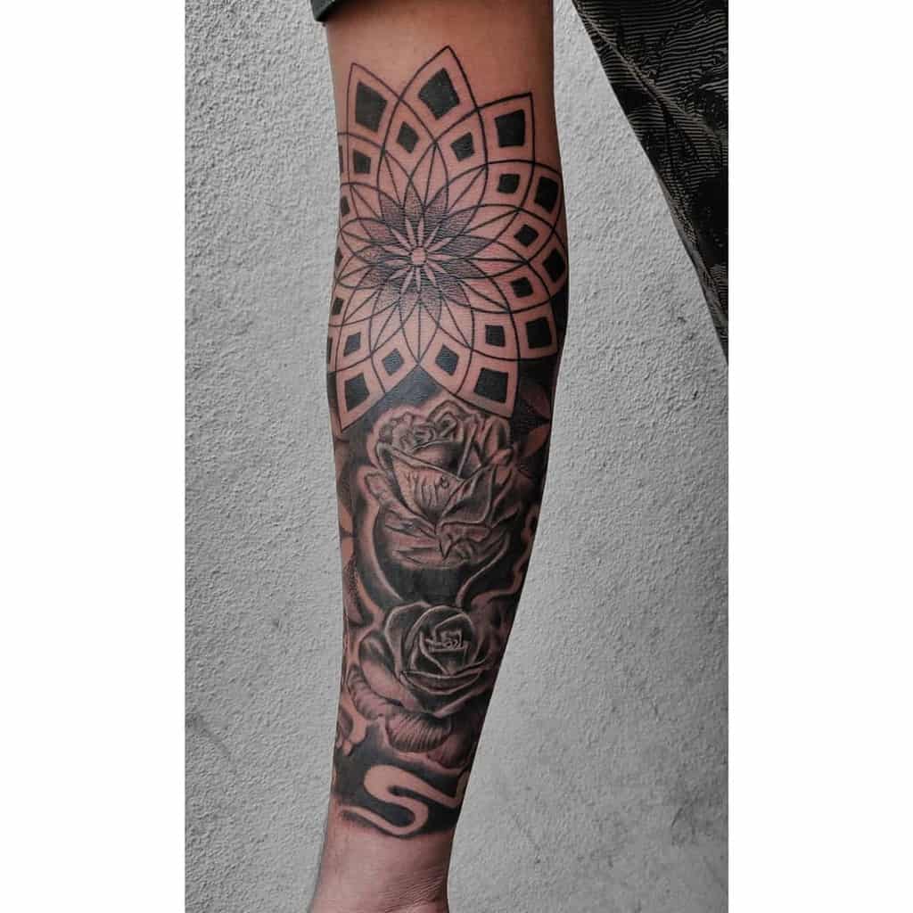 Forearm sleeve tattoo featuring a geometric mandala pattern intertwined with detailed roses in black and grey ink