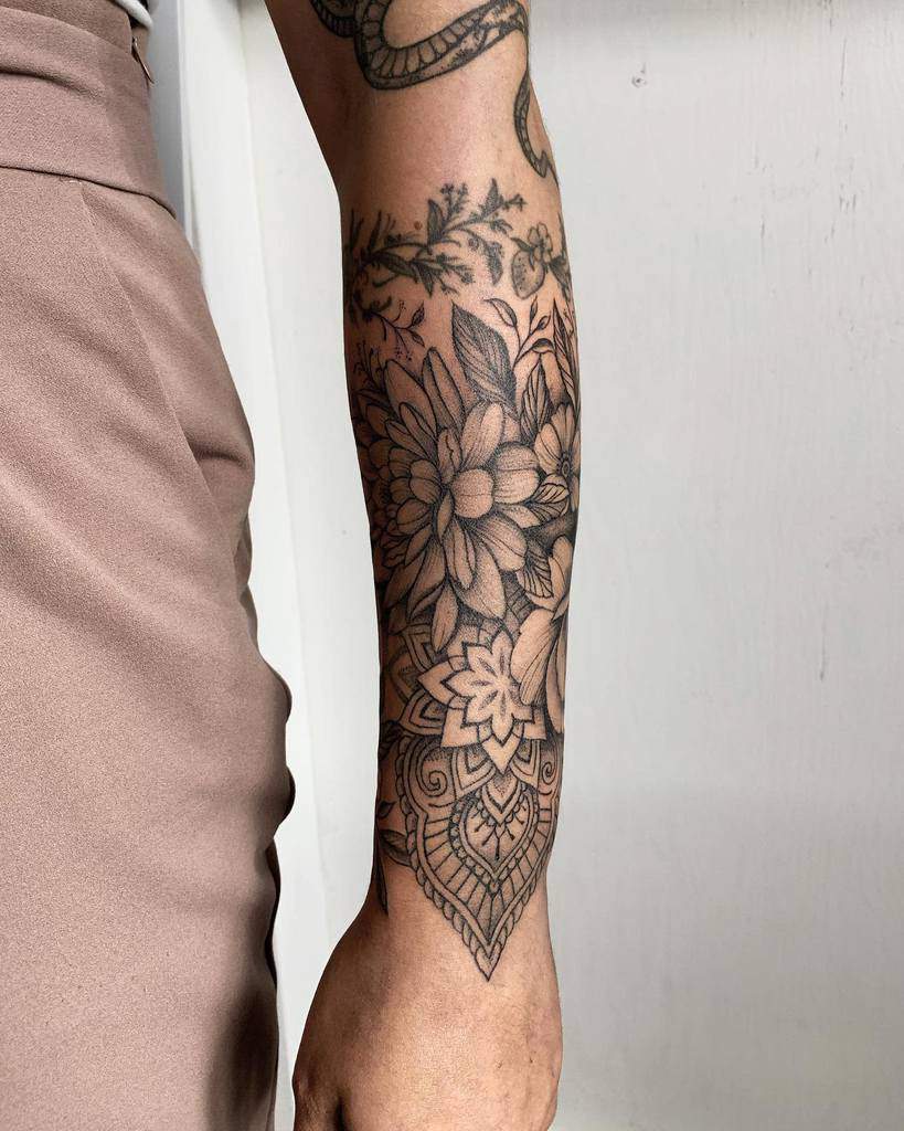 A stunning floral and geometric mandala sleeve tattoo elegantly wraps around a forearm