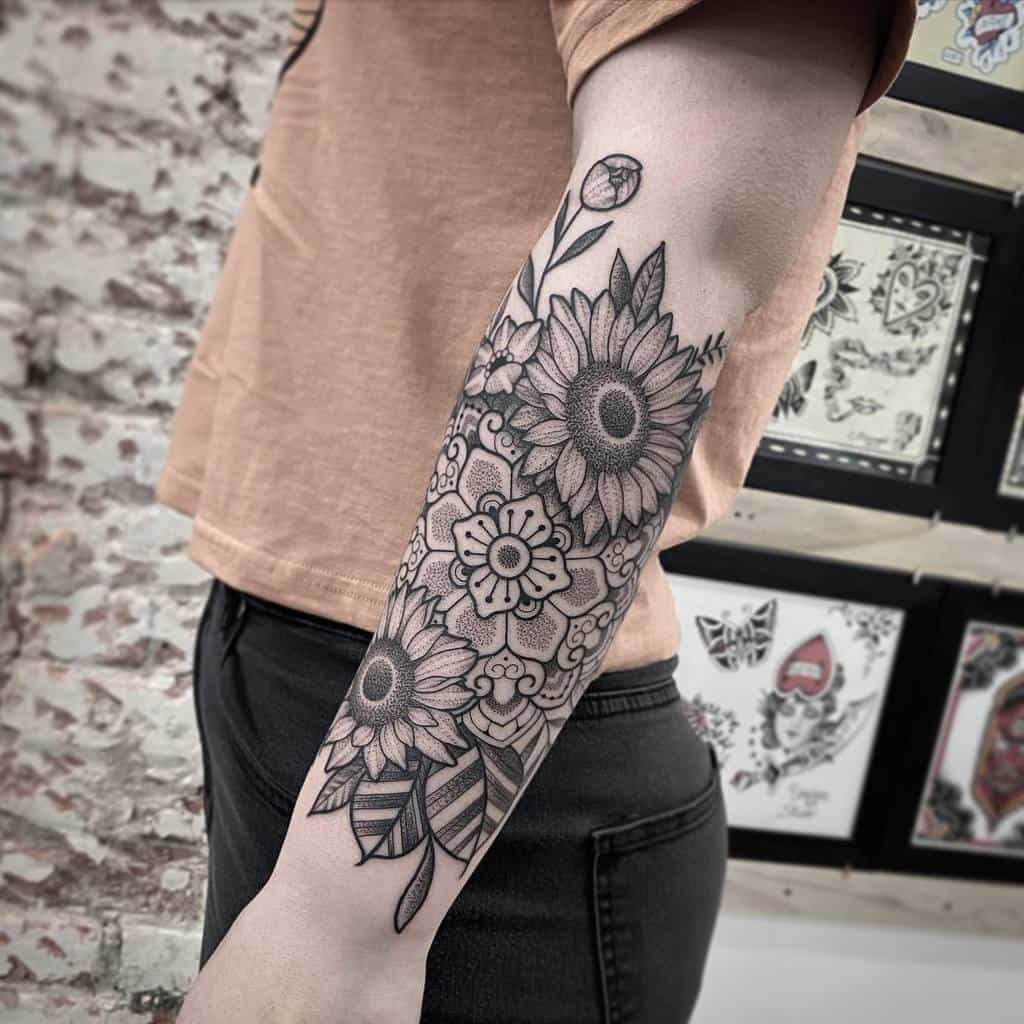 Forearm tattoo of sunflowers and leaves in black ink