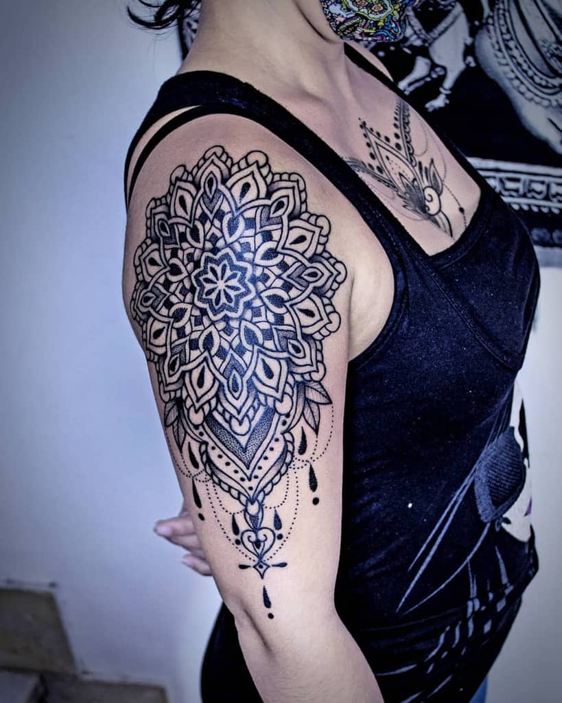 Tattooed mandala pattern on an upper arm, featuring intricate black details and dot work