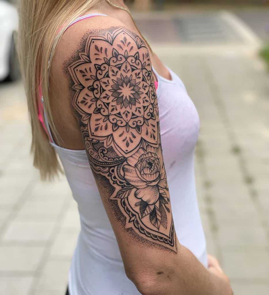 A woman with an intricate floral and mandala tattoo covering her upper arm