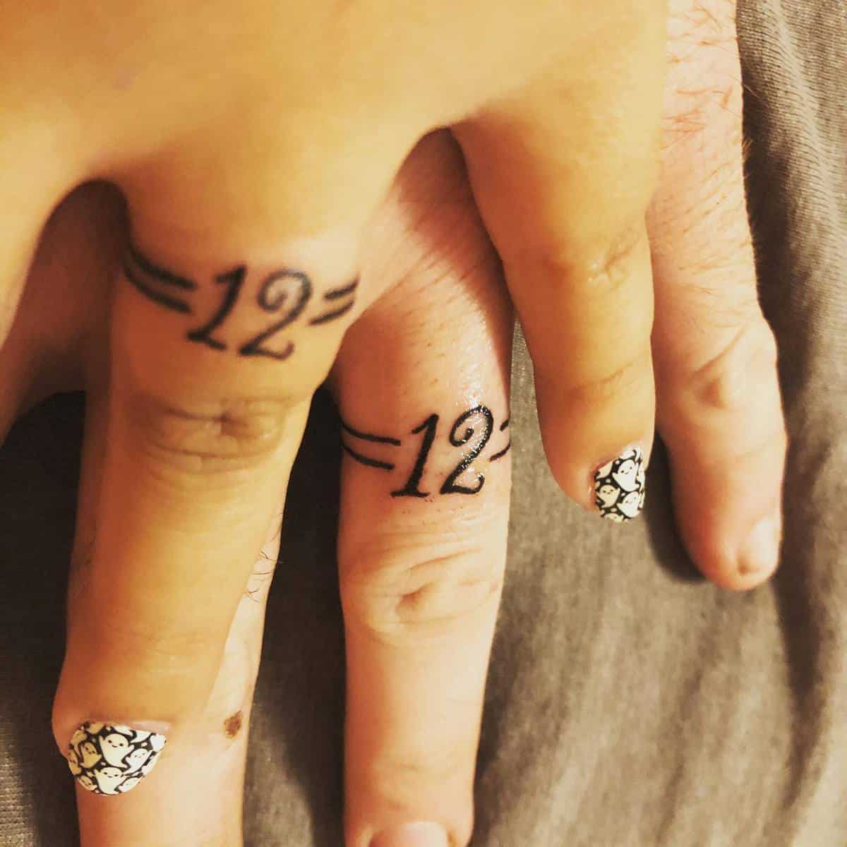 Close-up of two fingers with matching "=12=" tattoos