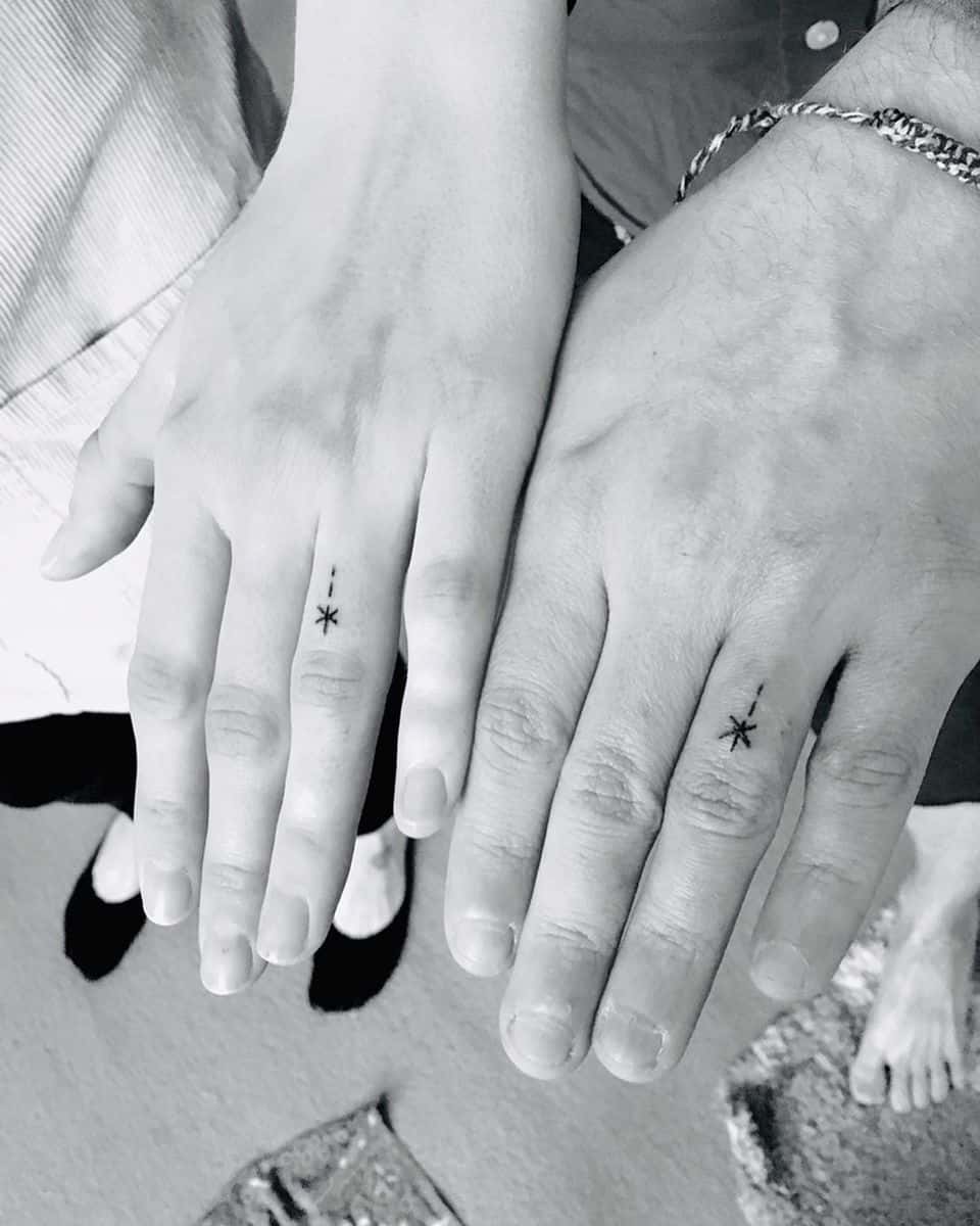 Two hands with matching minimalist star tattoos on their ring fingers