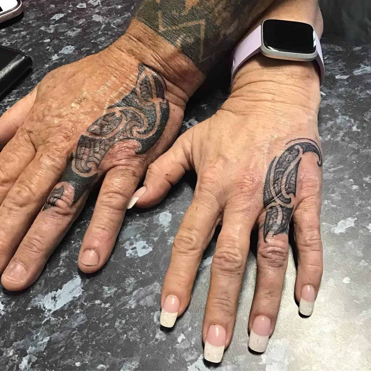 Two hands with black tribal tattoos