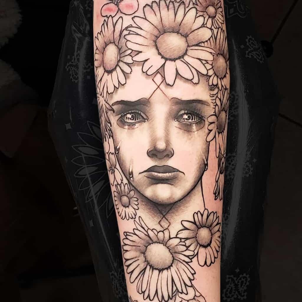 Forearm tattoo large surreal black and grey crying May Queen framed by daisies
