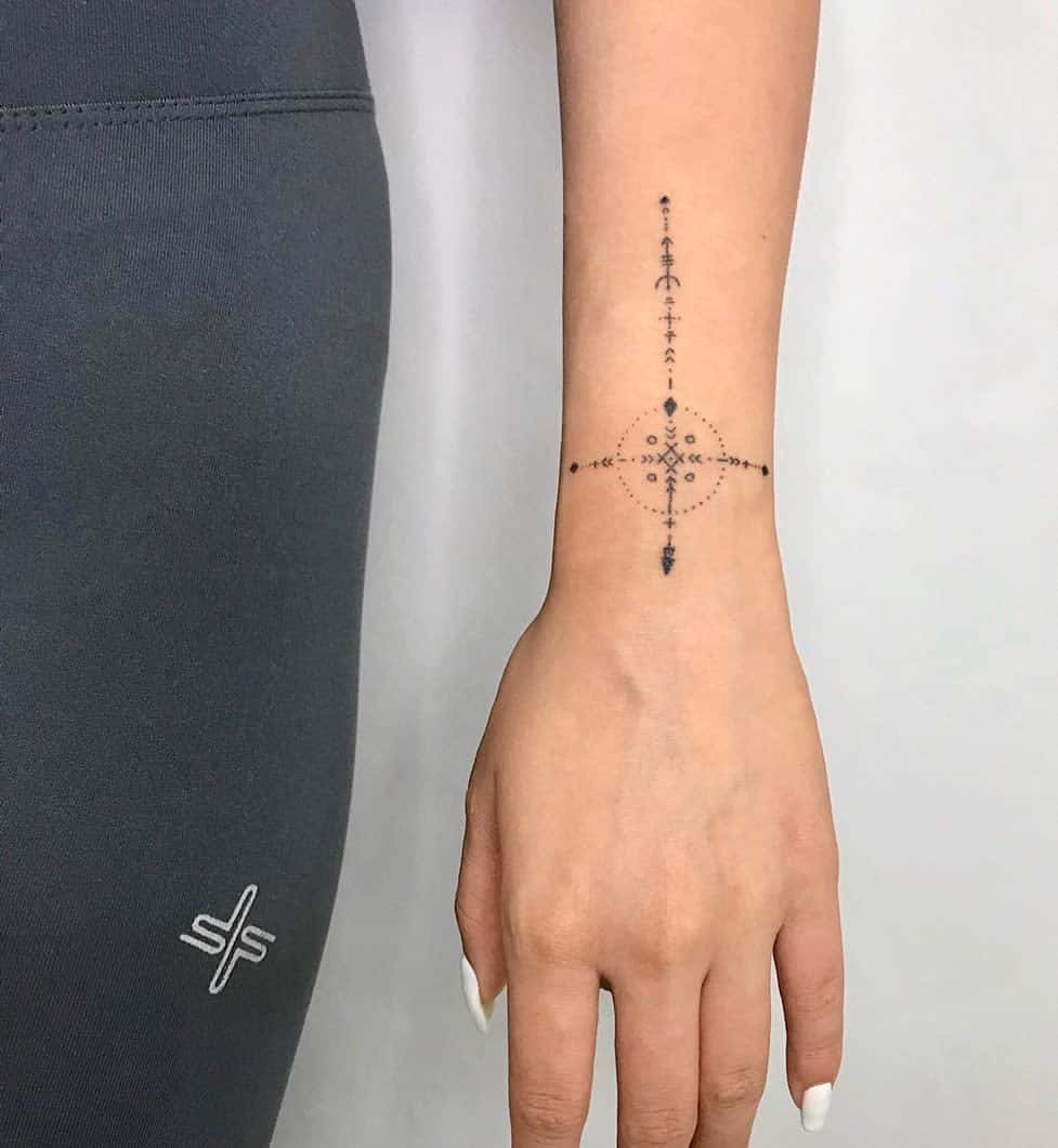 Tattoo on forearm featuring a geometric compass-like design with intricate dotwork details