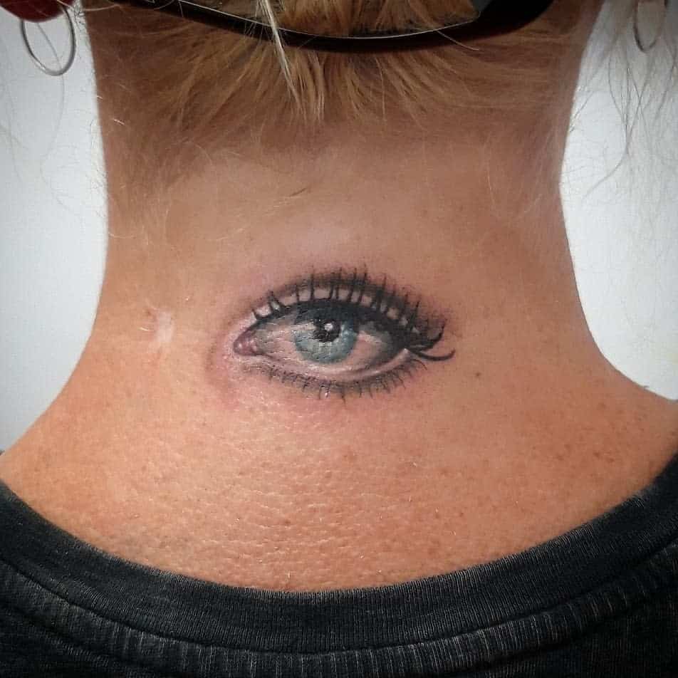 Tattoo of a realistic eye inked meticulously on the back of the neck