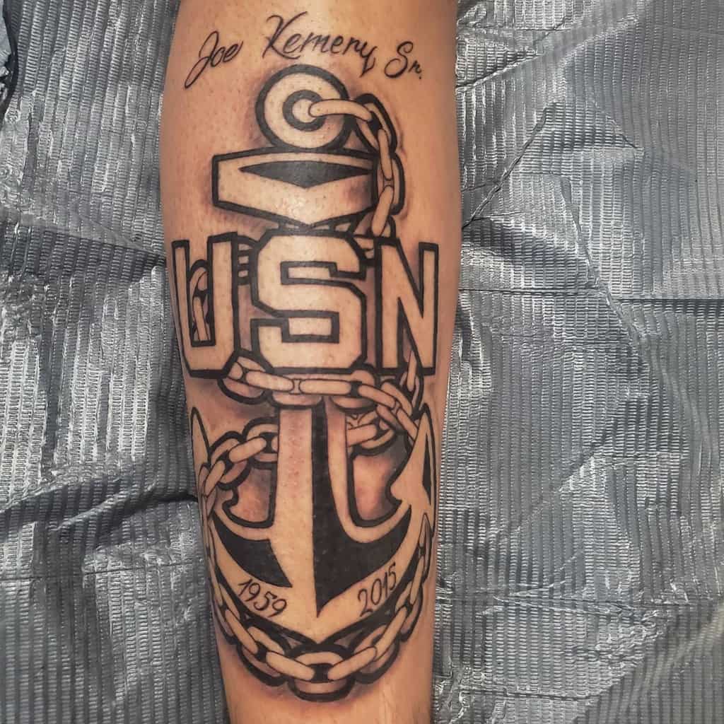 Tattoo of a navy anchor with "USN" and dates "1959 - 2005" on a person's forearm