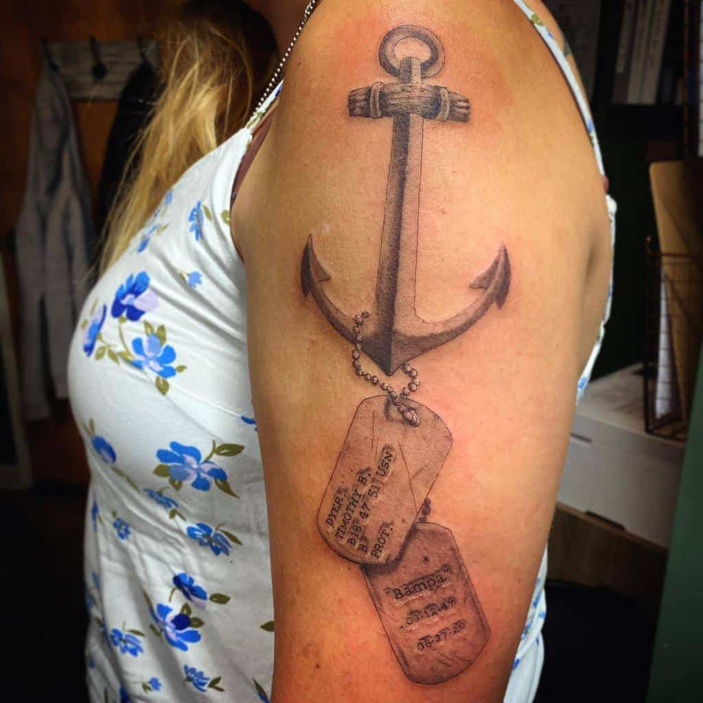 Navy anchor tattoo with dog tags on a woman's upper arm