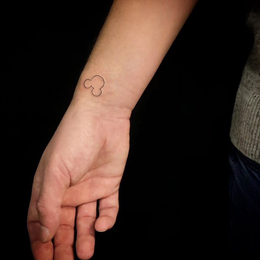 Simple, minimalistic tattoo of a small outline of Mickey Mouse's head placed on the wrist