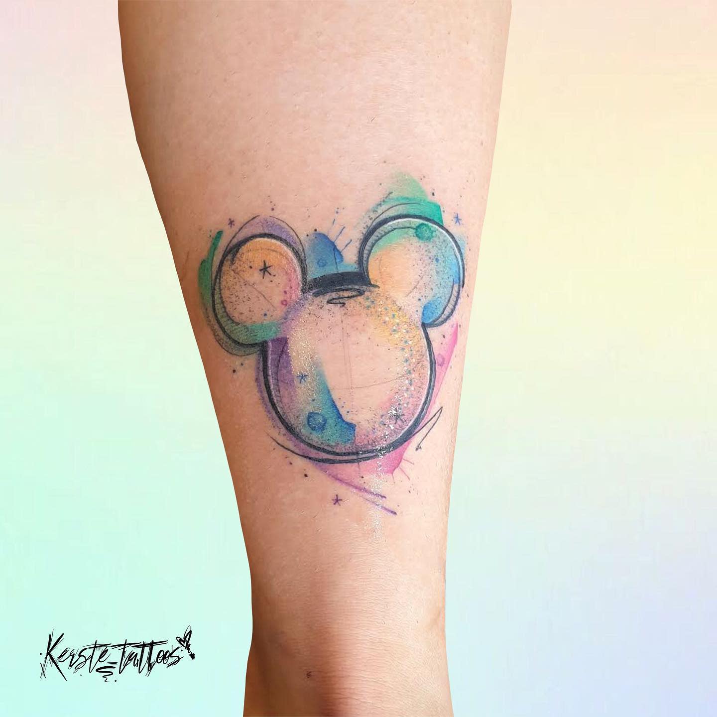 Watercolor tattoo of Mickey Mouse's head silhouette with vibrant pastel colors and abstract details