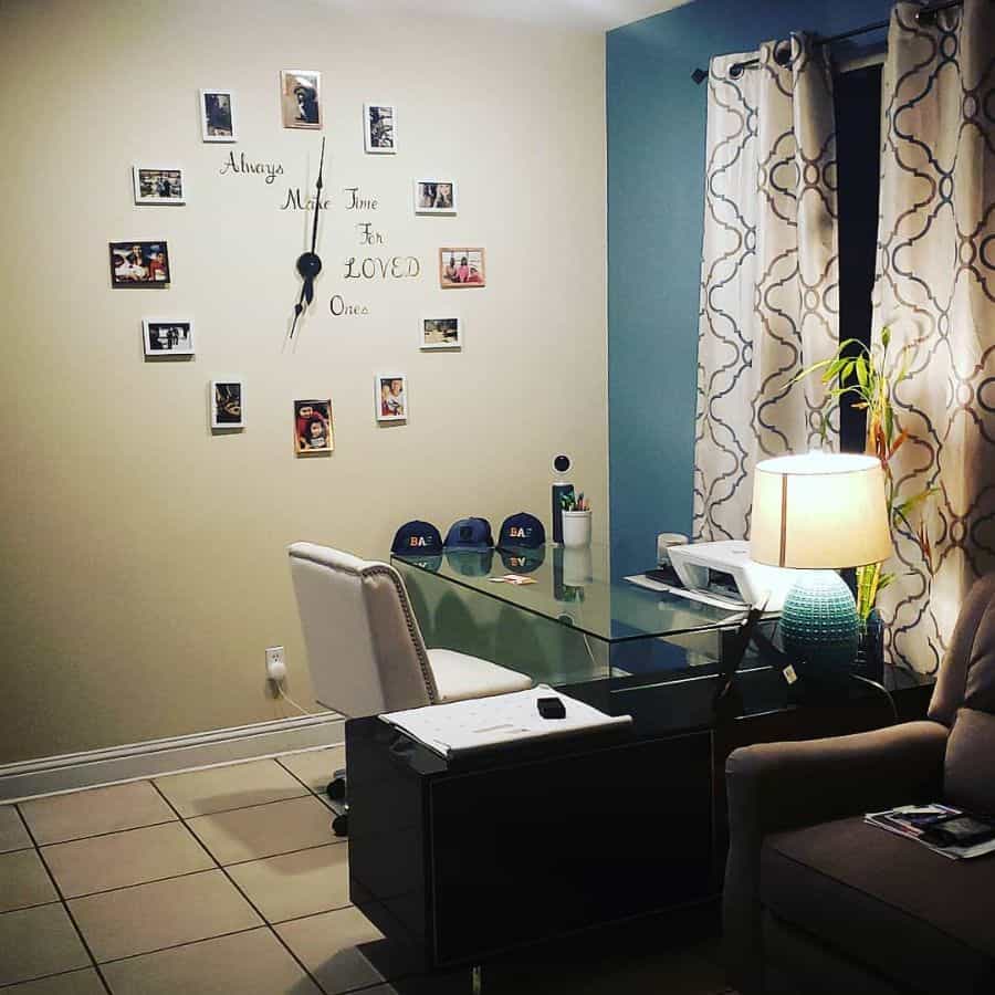 Cozy office with a glass desk, wall photo clock, lamp, and patterned curtains