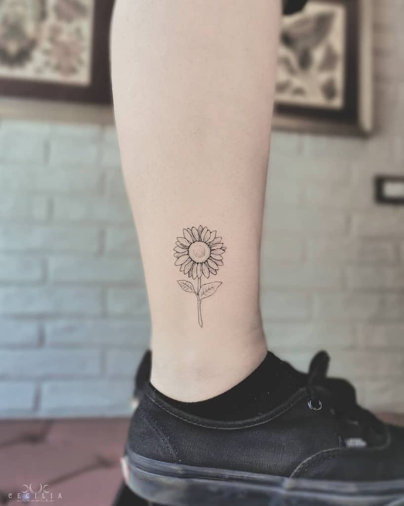 Minimalist sunflower tattoo on a calf