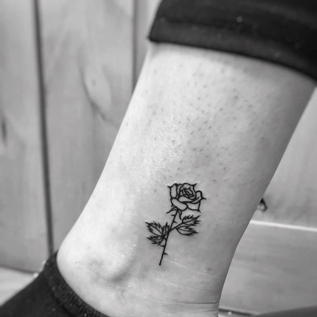 Black ink rose tattoo on an ankle
