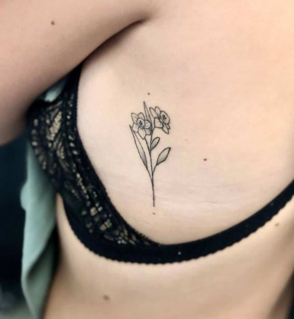 Delicate line drawing flower tattoo on a person's side