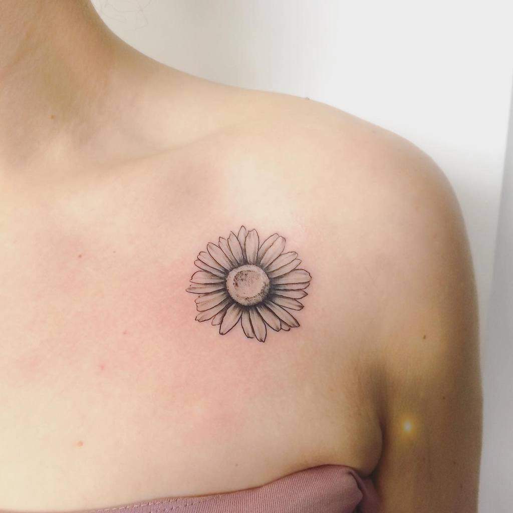 A sunflower tattoo on a person's upper chest near the shoulder