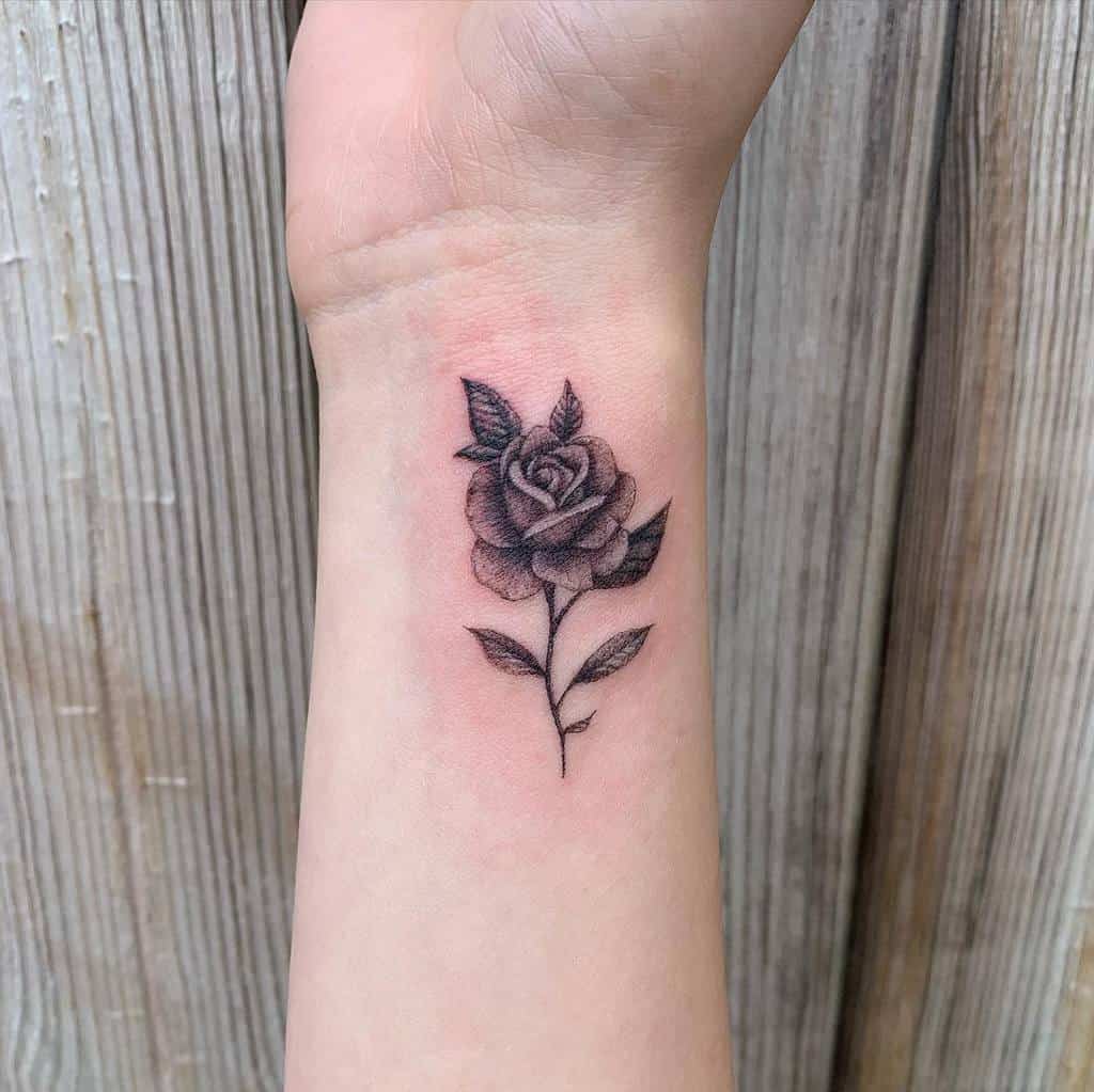 A black and gray rose tattoo on a wrist
