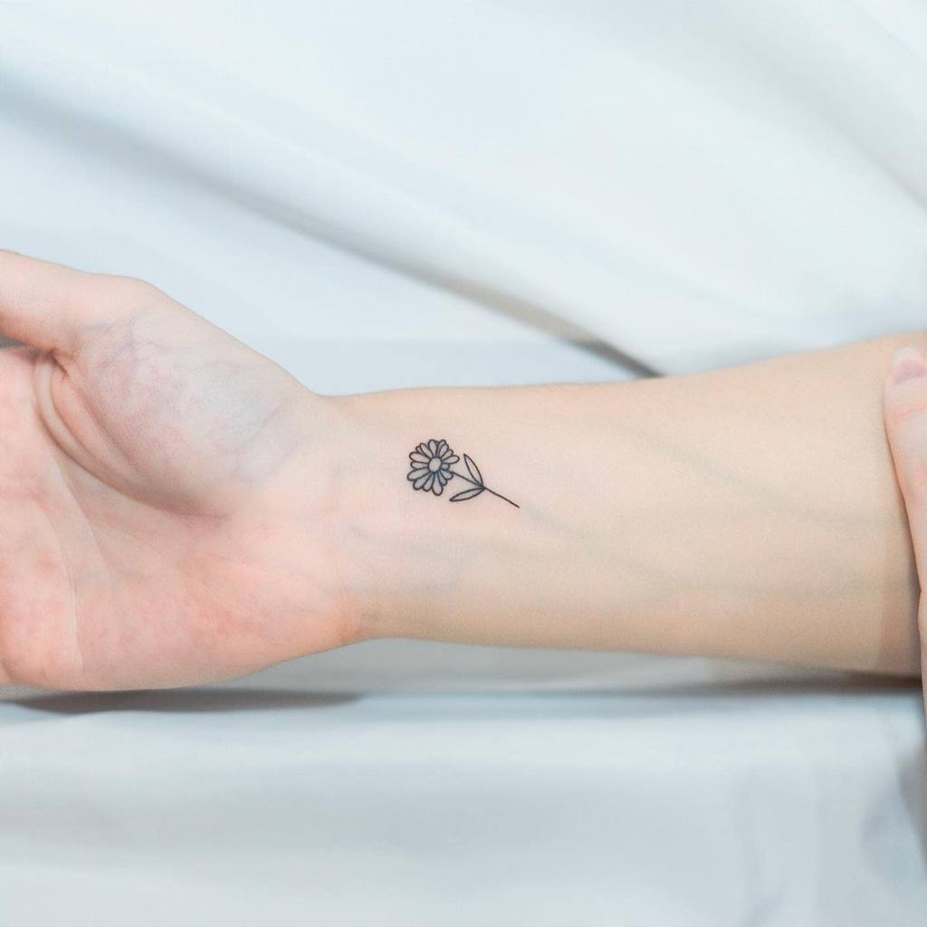 A small daisy tattoo on a wrist