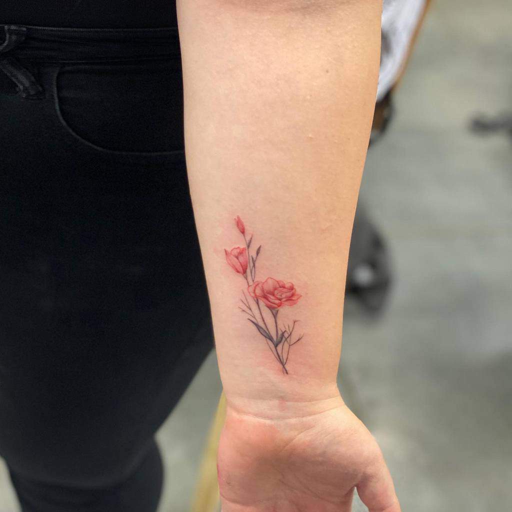 A small wrist tattoo of red flowers and black stems