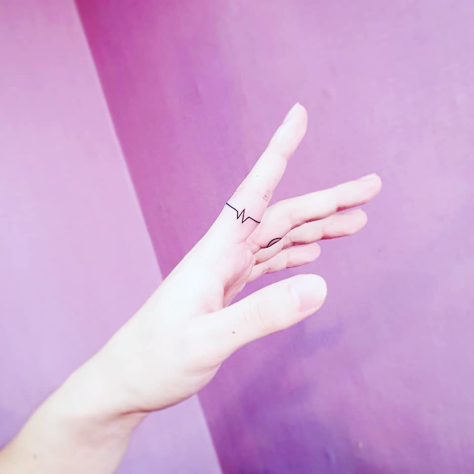 A sleek black ink ring tattoo of an electrocardiogram (ECG) line