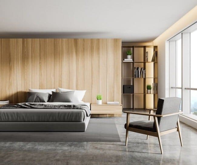 Minimalist bedroom with wooden accents, gray bedding, chair, and a window view