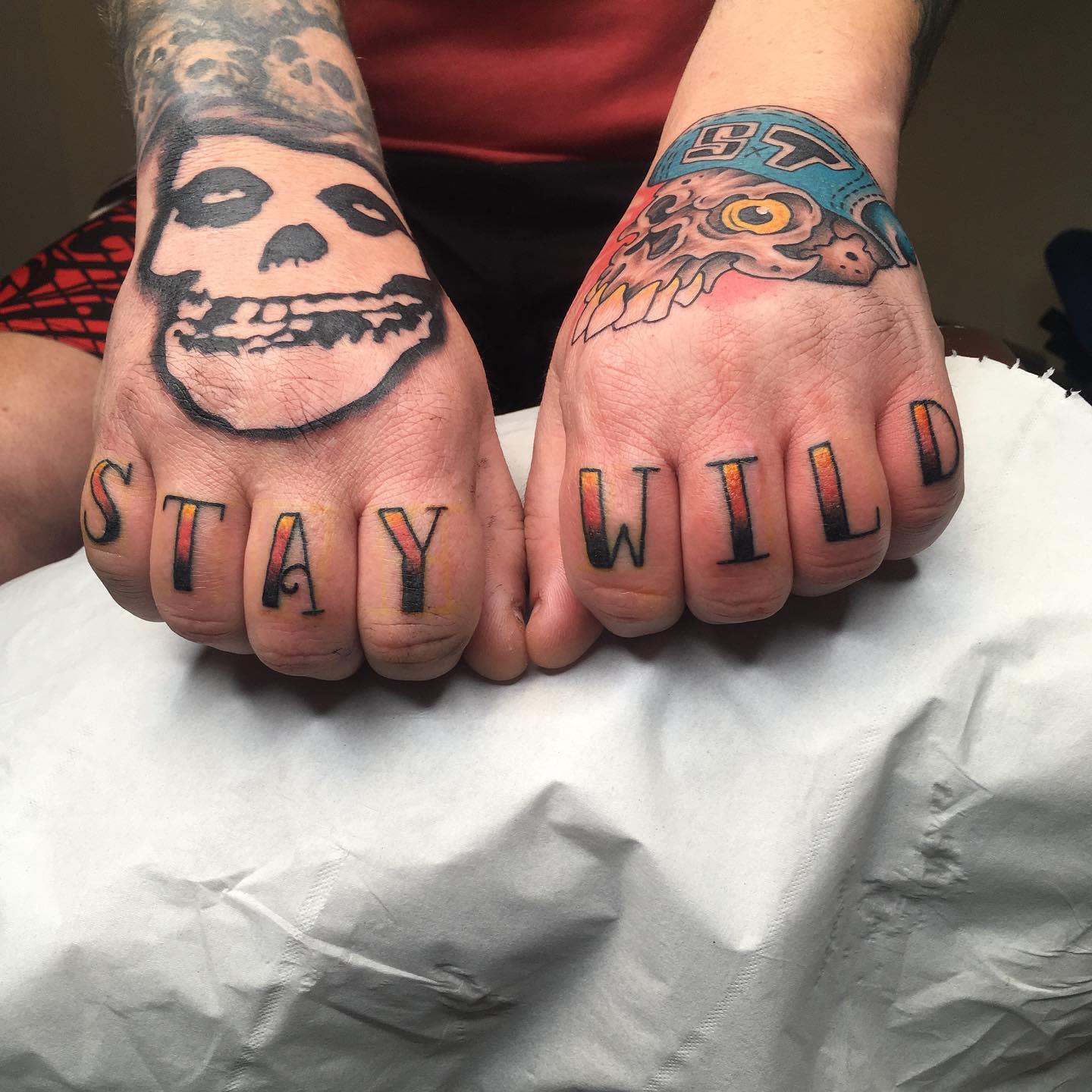 Tattooed fists with letters spelling "STAY WILD" and skull designs