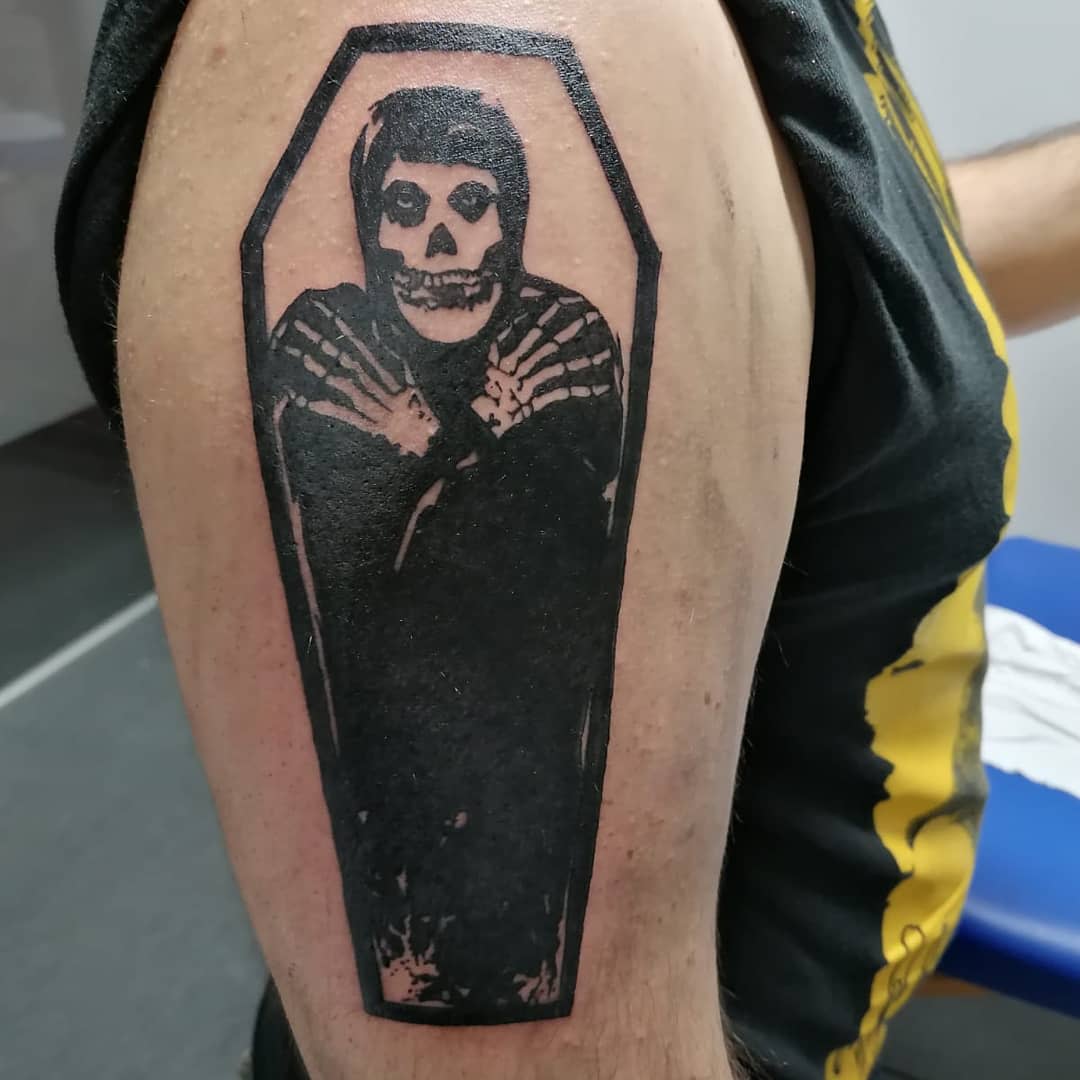 Tattoo of a skeleton in a coffin on an upper arm