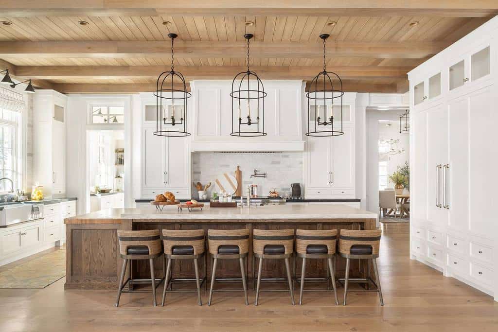 open plan kitchen white cabinets large wood island six seats bird cage lighting