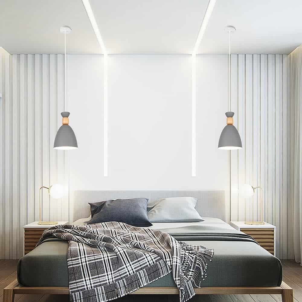 White minimalist bedroom with gray platform bed pendant lights and plaid blanket.