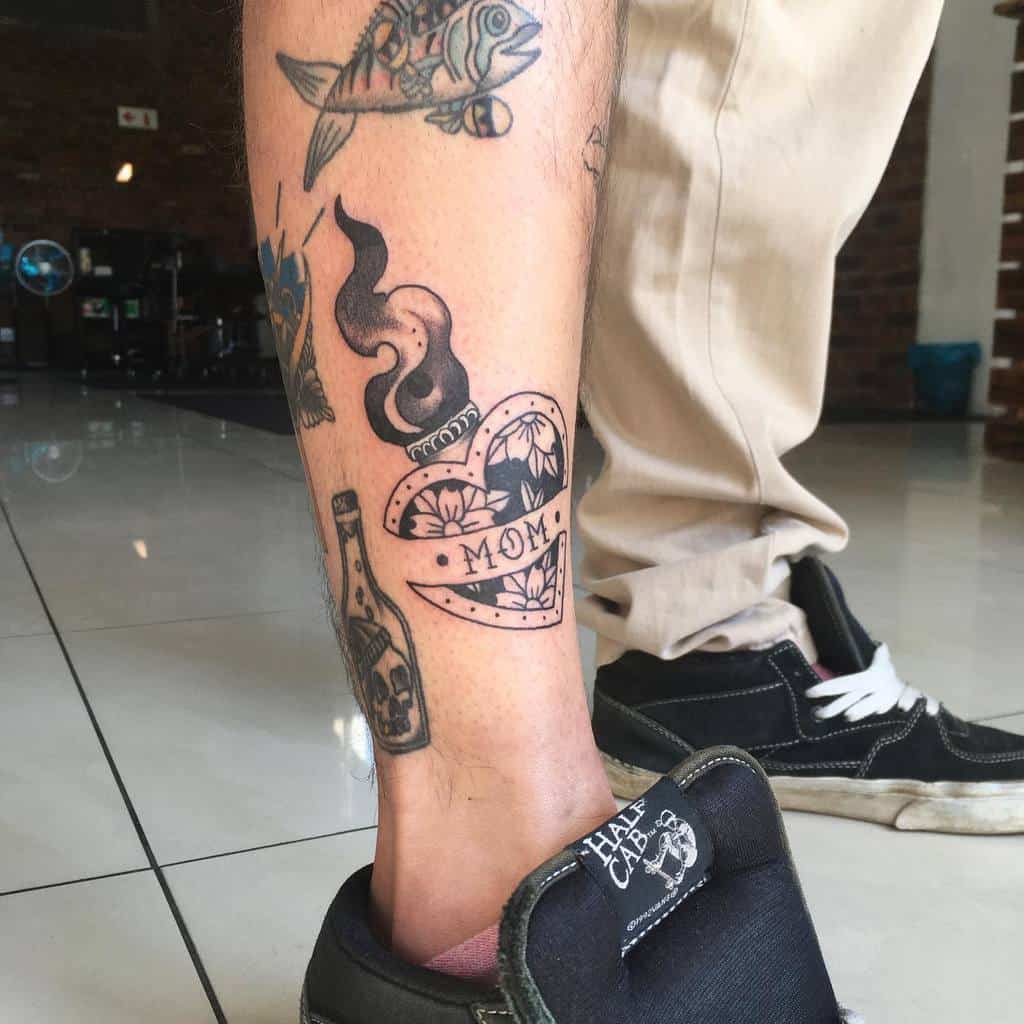 Man's leg adorned with various tattoos, featuring a heart with a "Mom" banner, along with a bottle and fish