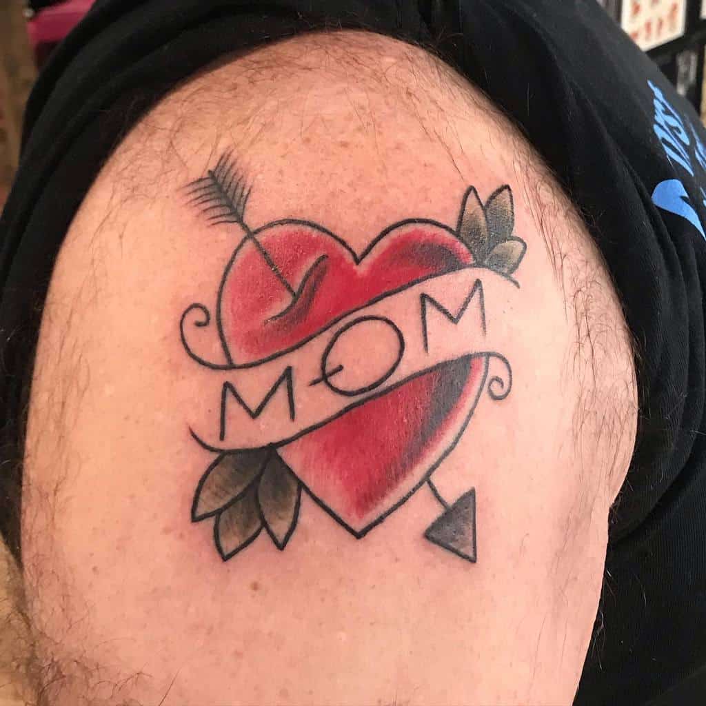 Tattoo of a heart with a "MOM" banner and an arrow piercing through, proudly displayed on an upper arm