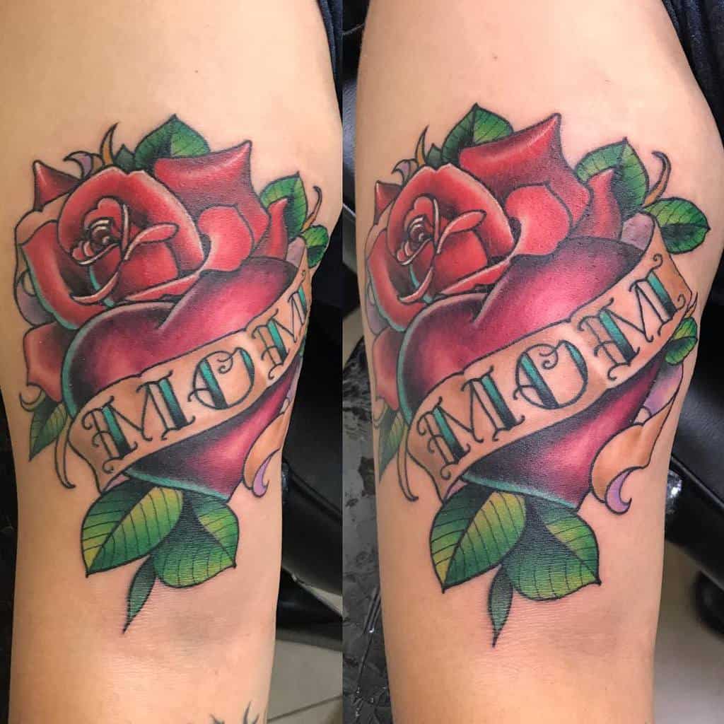 Traditional tattoo of a red heart with a banner reading 'MOM,' surrounded by a detailed red rose and green leaves in bold colors