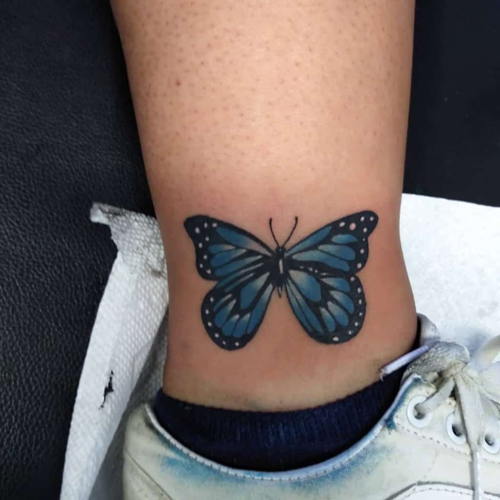 A blue butterfly tattoo delicately graces an ankle