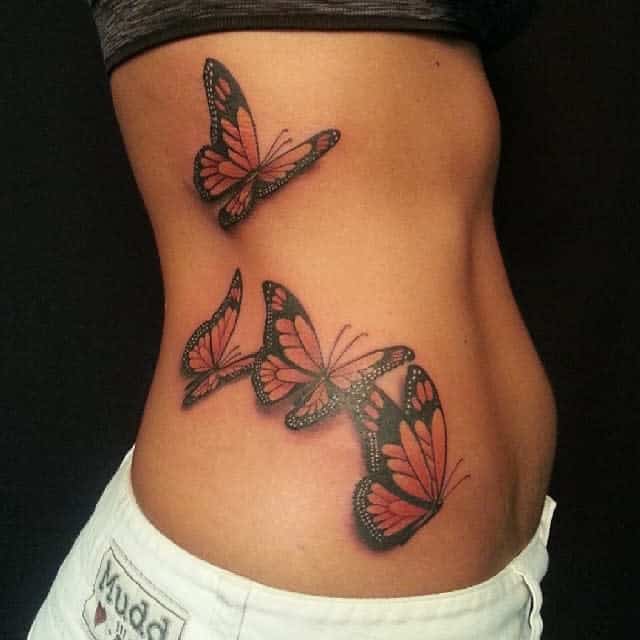 Monarch butterfly tattoos adorn a woman's side, showcasing vibrant orange and black wings in graceful flight