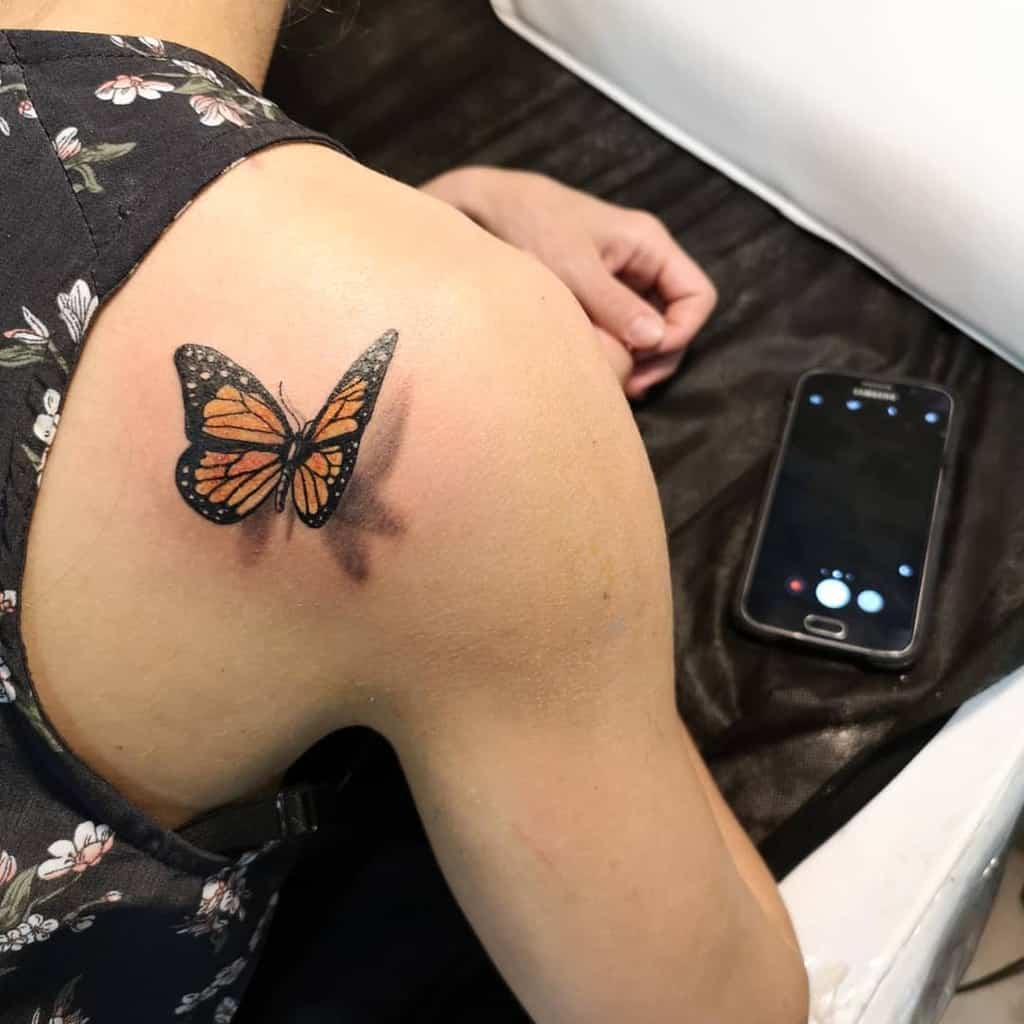 A person with a monarch butterfly tattoo on their shoulder